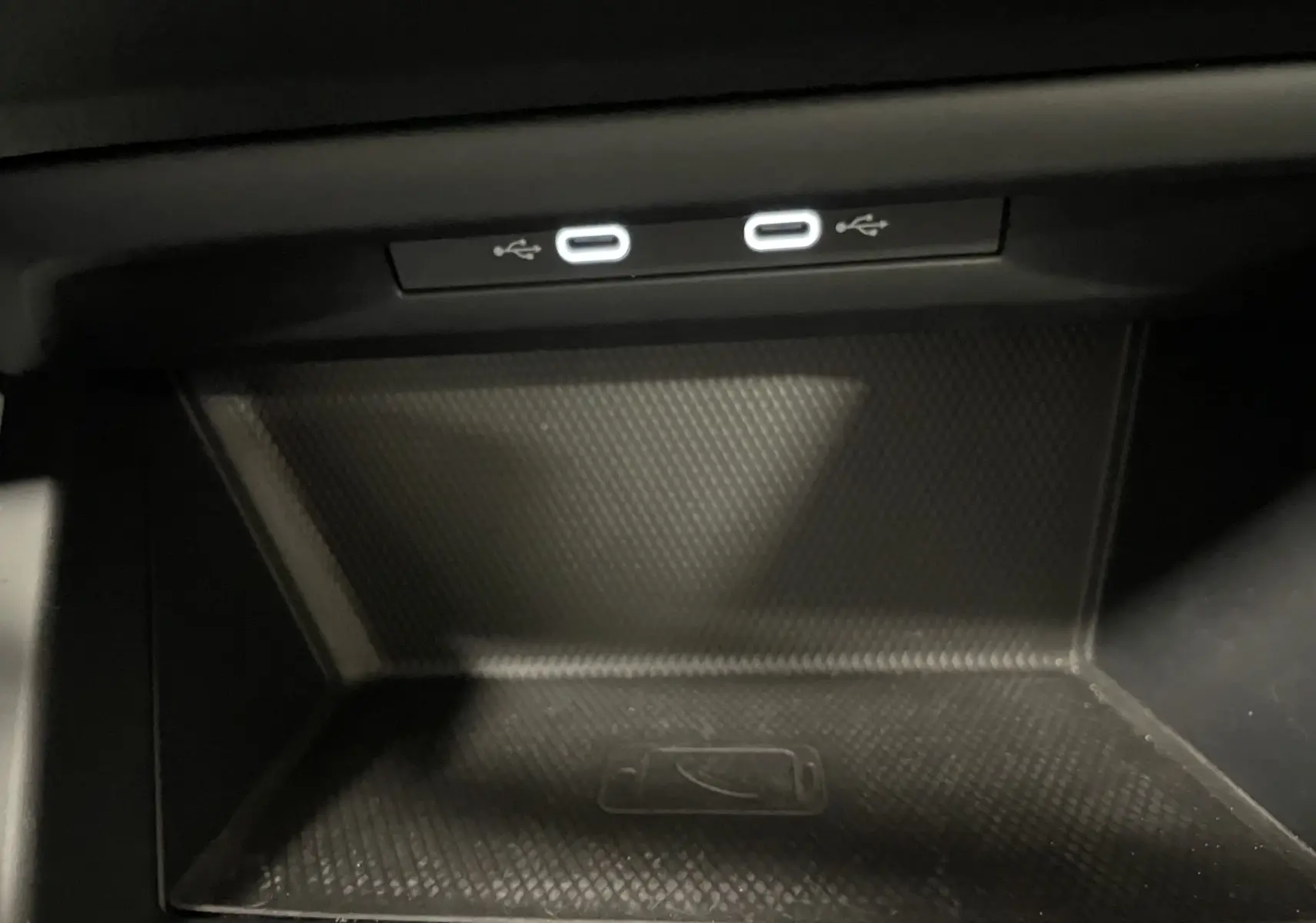 Gros plan sur la zone de recharge sans fil et deux ports USB-C éclairés dans la console centrale d'une Volkswagen Golf Bleu Atlantique 2023.