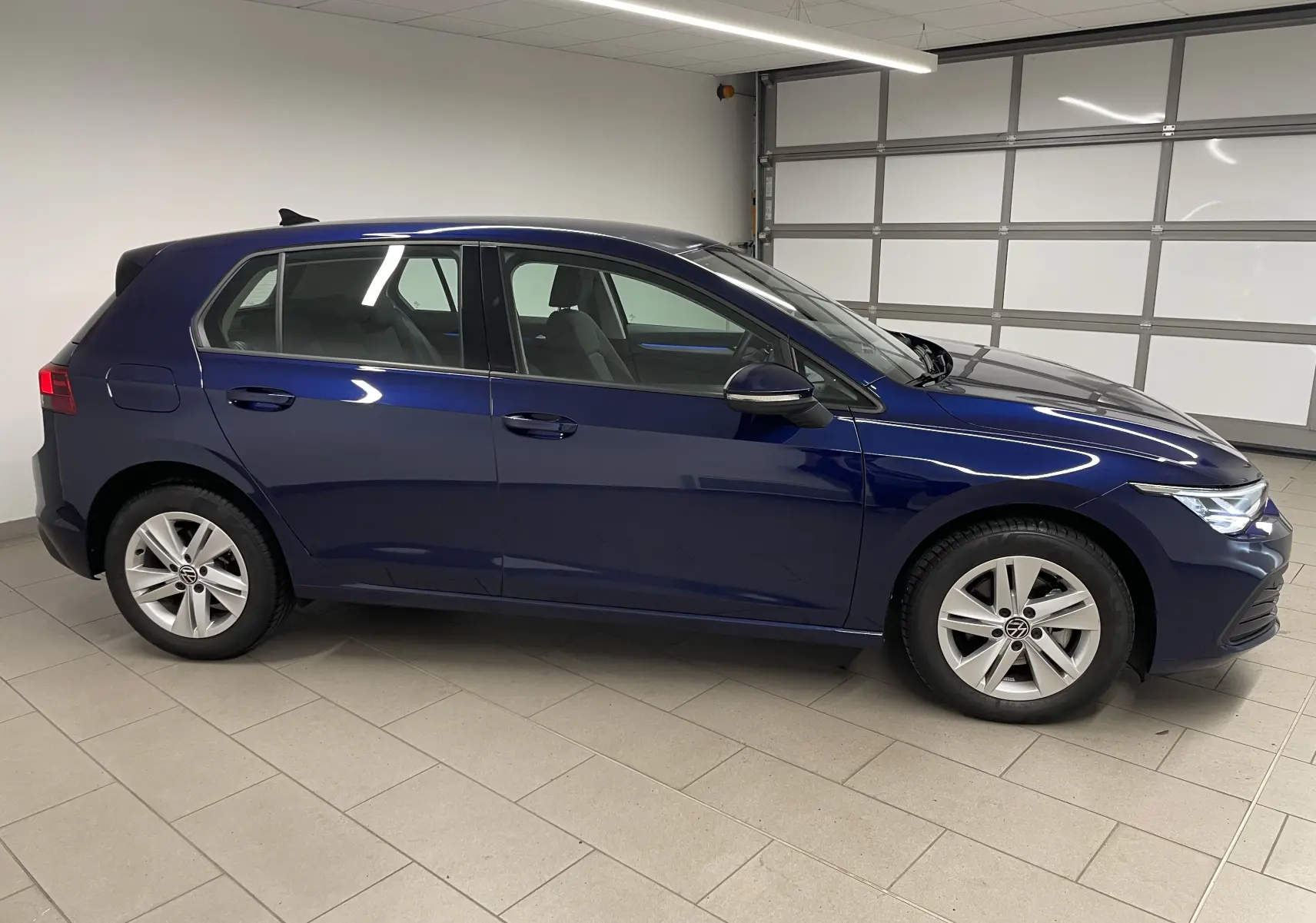 Volkswagen Golf 1.0 TSI 110 DSG7 Life Plus 2023 en bleu Atlantique vue de profil côté gauche dans un garage.