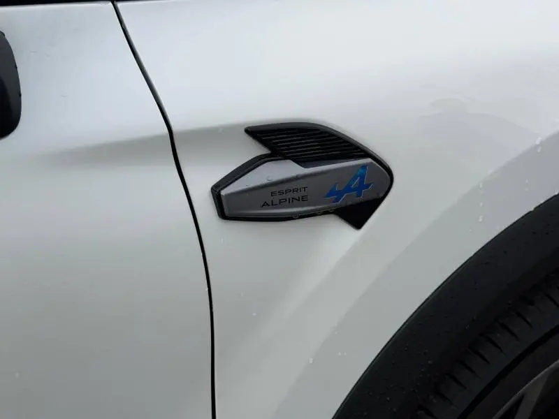 Gros plan sur l'aile avant gauche blanche nacrée du Renault Captur avec logo Esprit Alpine bleu et noir.