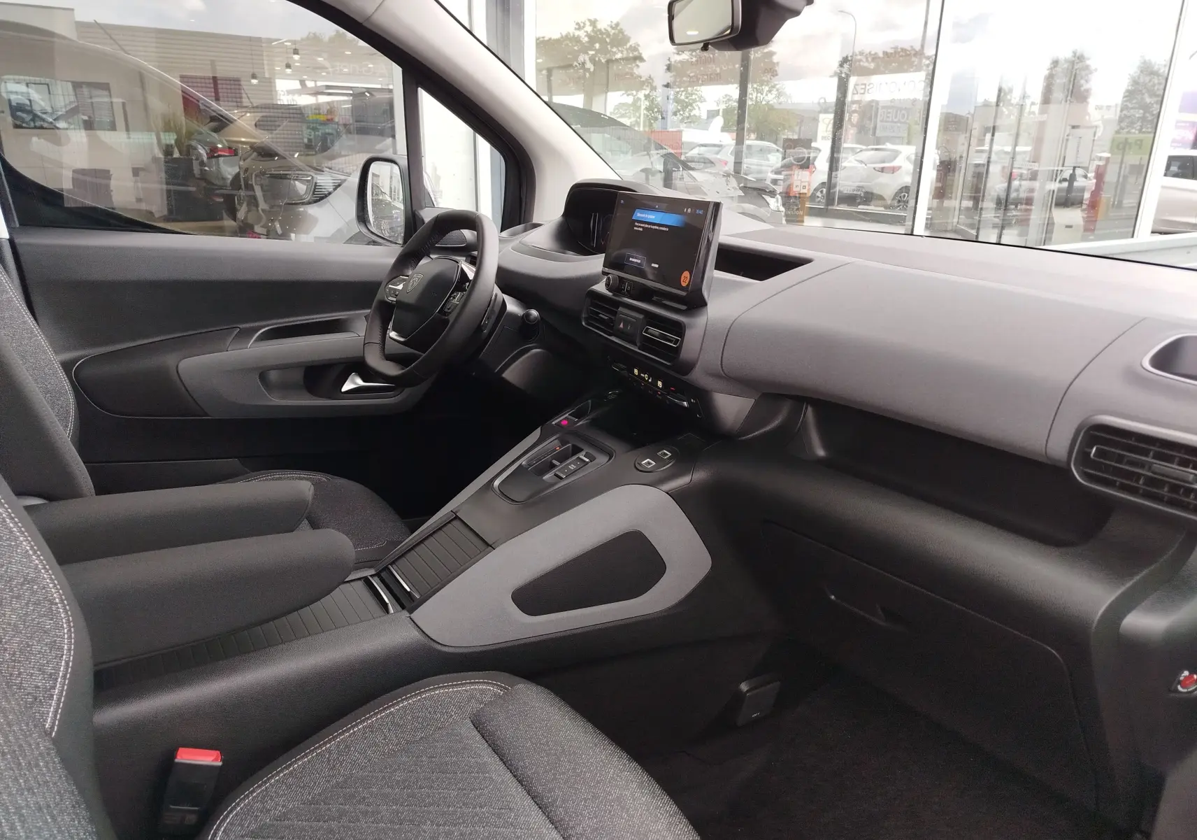Vue intérieure côté conducteur du Peugeot Rifter 2026 noir Perla Nera, avec tableau de bord moderne et écran tactile central.