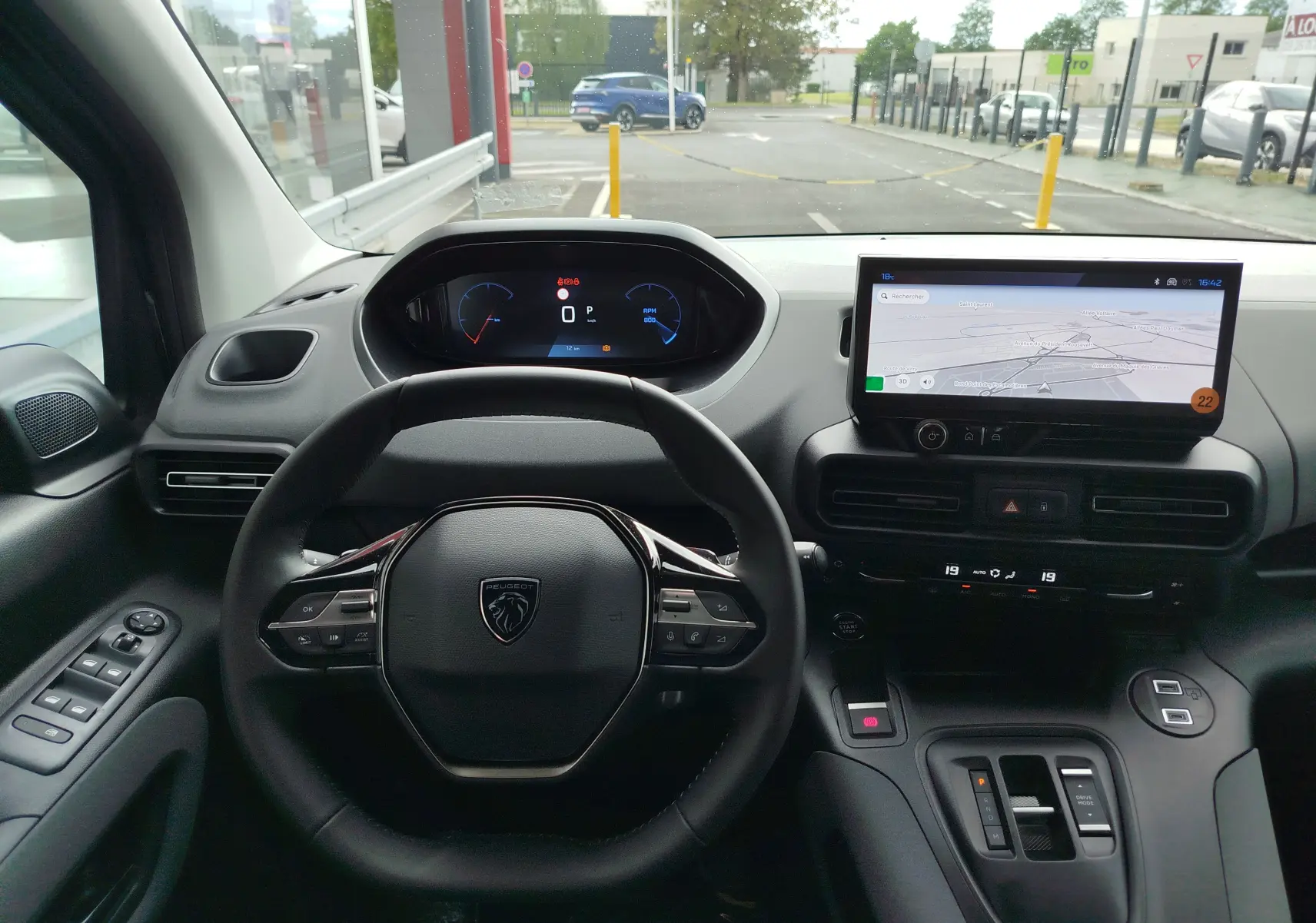 Vue intérieure du tableau de bord du Peugeot Rifter noir Perla Nera, avec volant multifonction et écran tactile central affichant la navigation.