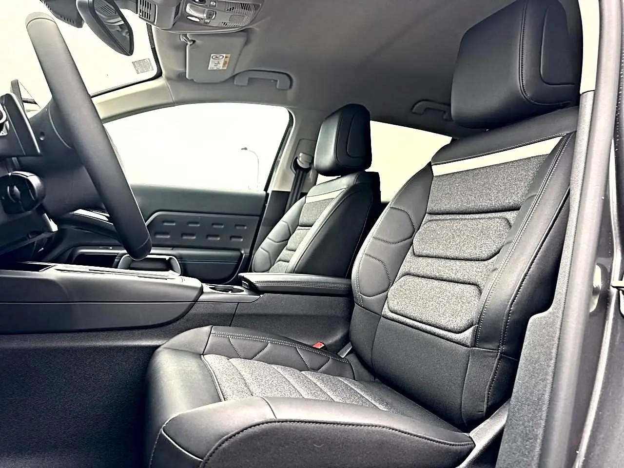Vue intérieure côté conducteur du Citroën C5 Aircross 2025, sièges tissu brun et cuir noir avec accoudoir central.