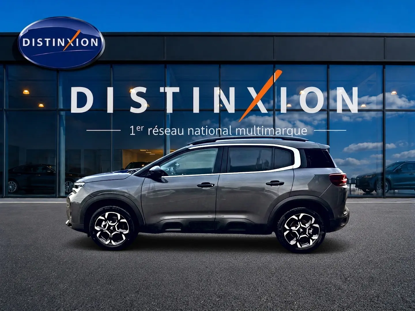 Profil côté gauche du Citroën C5 Aircross gris platinium 2025 avec jantes alu et barres de toit visibles.