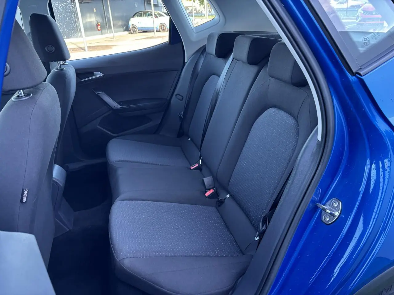 Vue intérieure côté droit sur la banquette arrière noire du SEAT Arona bleu saphir avec porte ouverte.