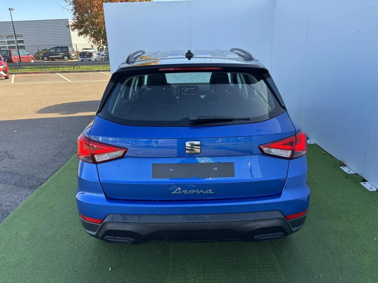 Vue arrière d'un SEAT Arona bleu saphir avec toit noir, feux arrière LED et double sortie d'échappement intégrée.