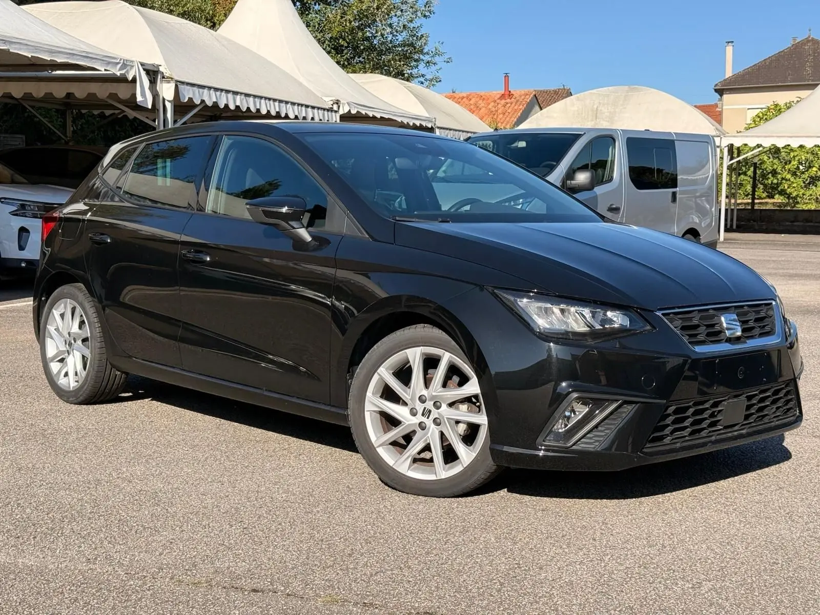 SEAT Ibiza 1.0 TSI 95 FR noire vue en 3/4 avant droit, avec jantes argentées et feux LED allumés.