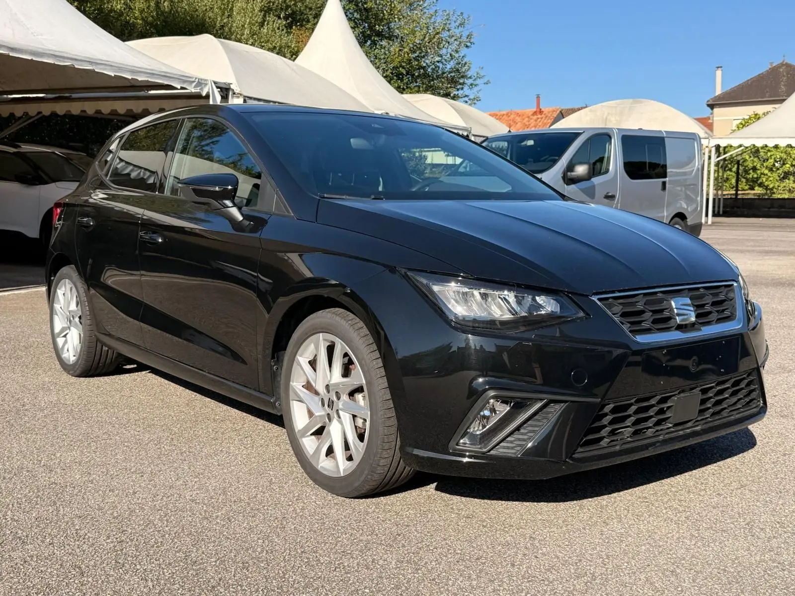 SEAT Ibiza 1.0 TSI 95 FR noire vue en 3/4 avant droit, avec jantes argentées et phares LED allumés.