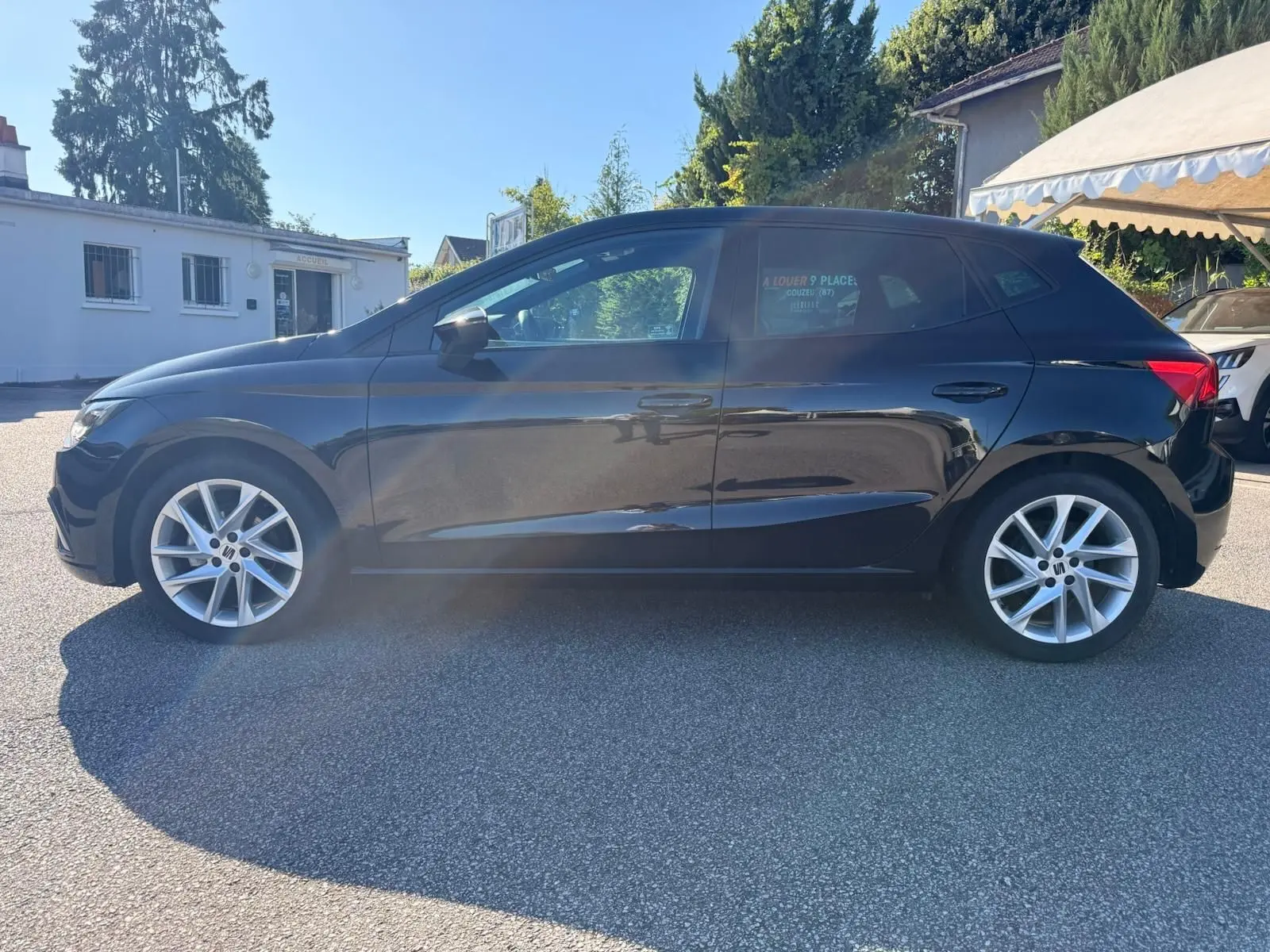 Profil latéral droit d'une SEAT Ibiza noire 2025 avec jantes alliage et vitres teintées, stationnée en extérieur.