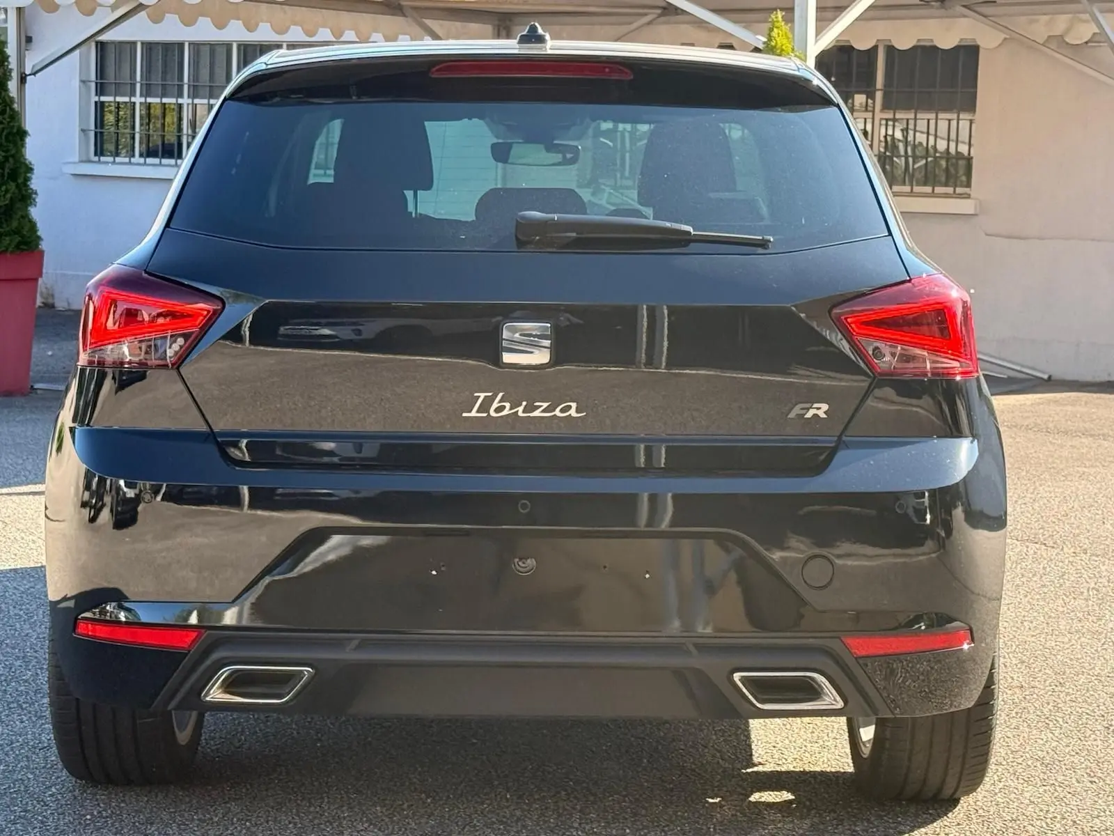 Vue arrière d'une SEAT Ibiza 1.0 TSI FR noire, avec feux LED triangulaires et double sortie d'échappement chromée.