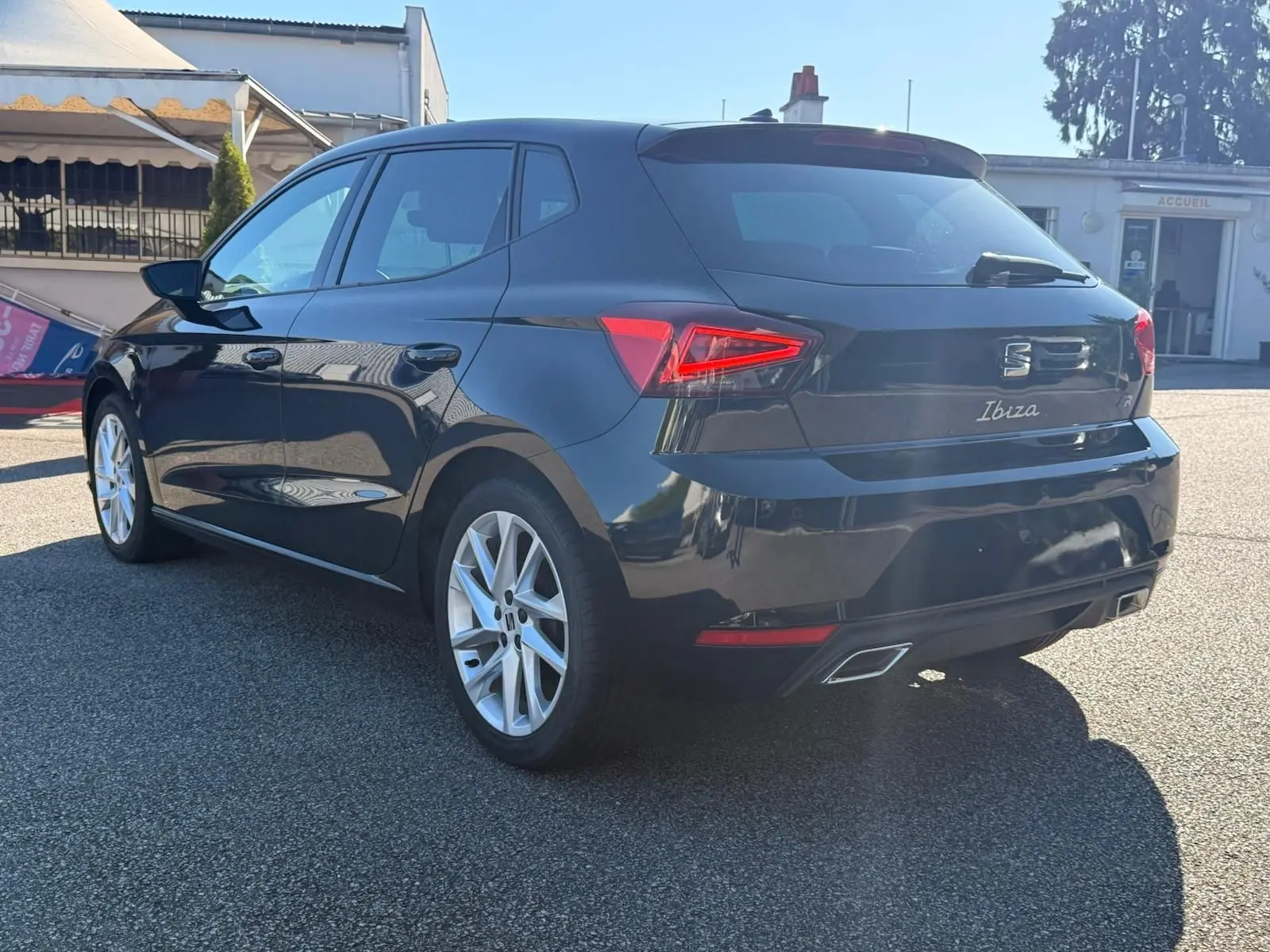 Vue 3/4 arrière droite d'une SEAT Ibiza noire 2025 avec feux LED et double sortie d'échappement chromée.