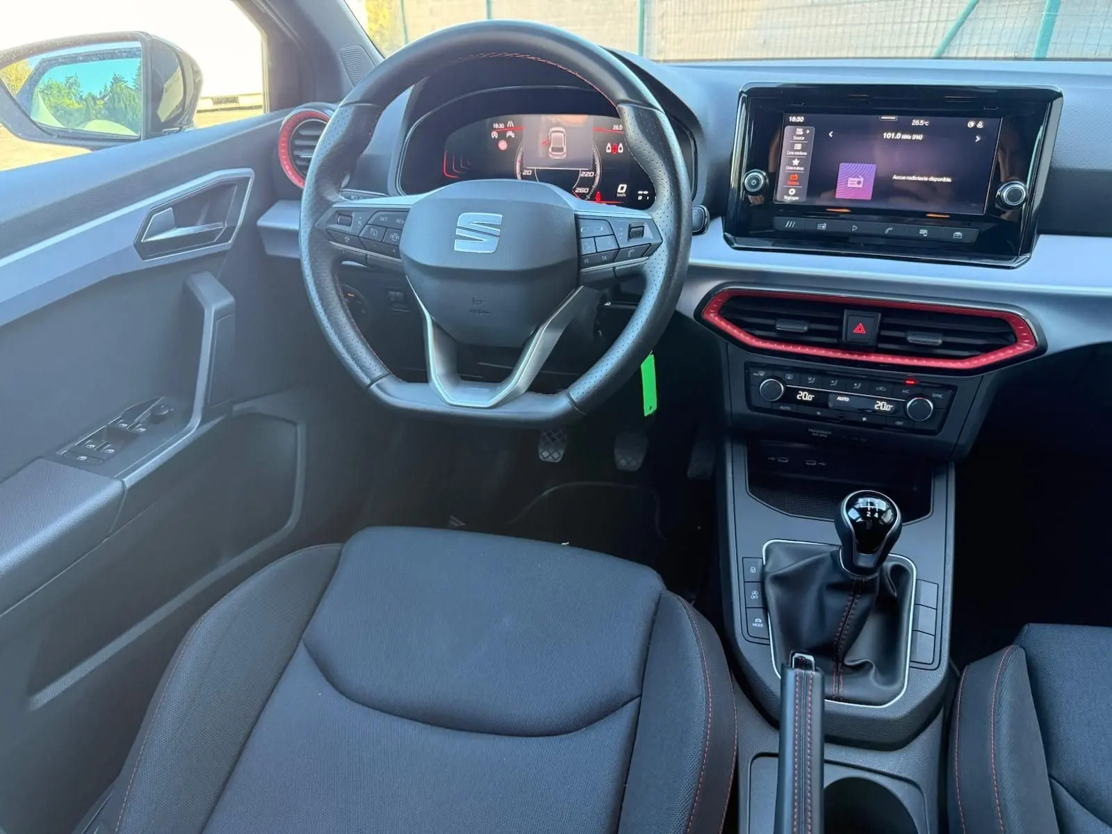 Vue intérieure avant du poste de conduite de la SEAT Ibiza noire, volant cuir multifonctions et écran tactile central.