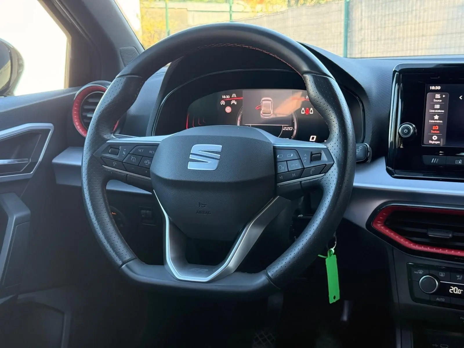 Vue intérieure centrée sur le volant cuir noir perforé de la SEAT Ibiza 2025 avec tableau de bord digital et écran tactile.