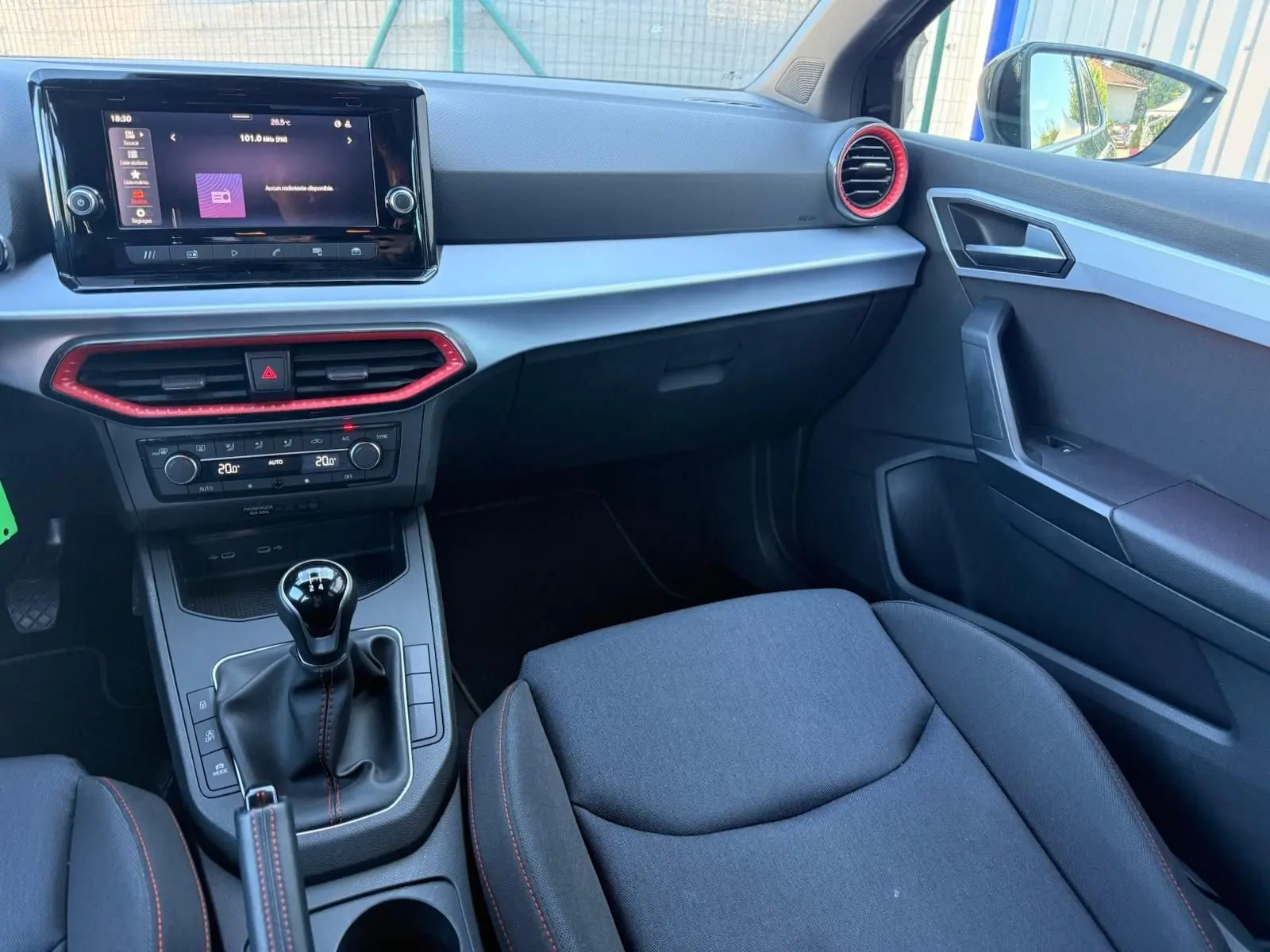 Intérieur avant droit de la SEAT Ibiza noire, tableau de bord avec écran tactile et détails rouges autour des aérateurs.