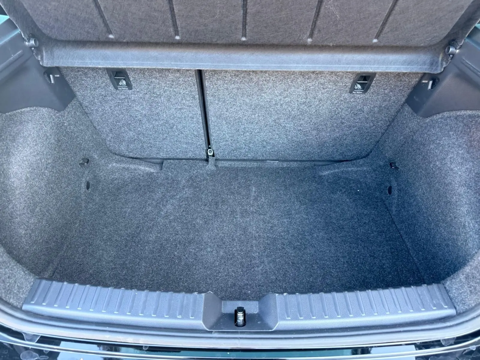 Vue plongeante sur le coffre vide de la SEAT Ibiza noire 2025, montrant la moquette grise et l'ouverture large.