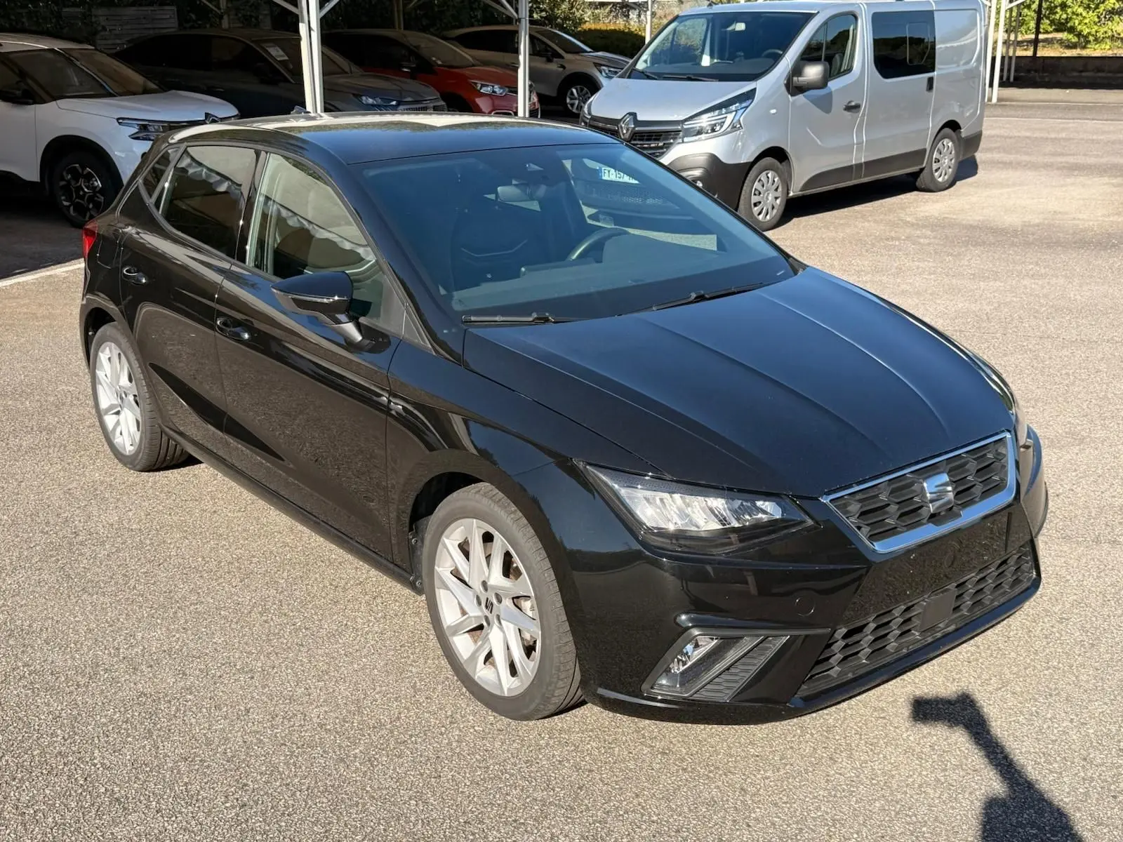 Vue 3/4 avant droite d'une SEAT Ibiza noire 2025 avec phares LED et jantes alliage argentées sur parking.