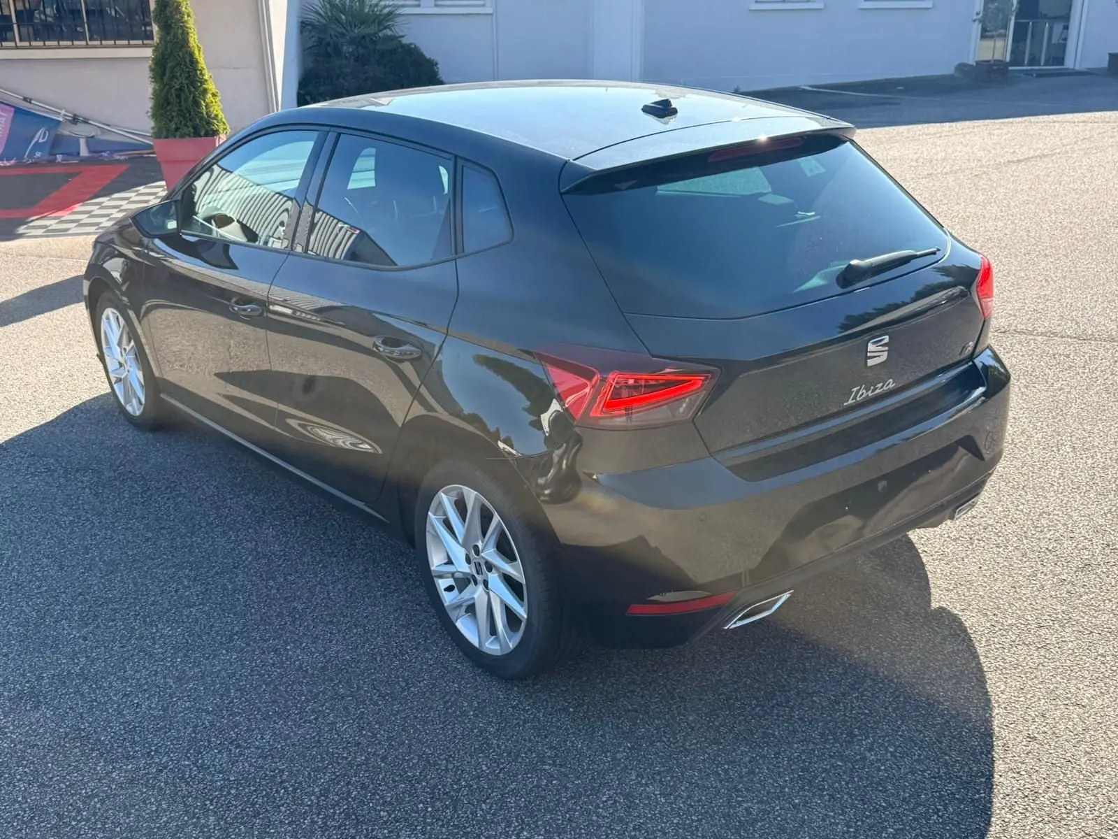 Vue 3/4 arrière droite d'une SEAT Ibiza noire 2025 avec feux arrière LED et jantes alliage argentées.