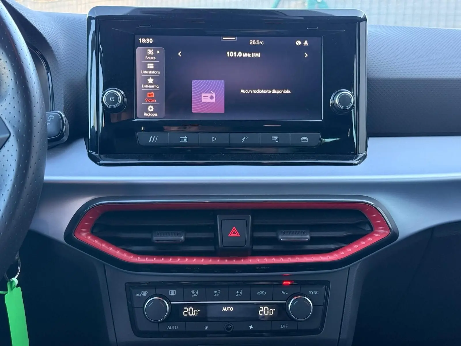 Vue rapprochée du tableau de bord central de la SEAT IBIZA 1.0 TSI 95 FR 2025 avec écran tactile et cadre d’aération rouge.