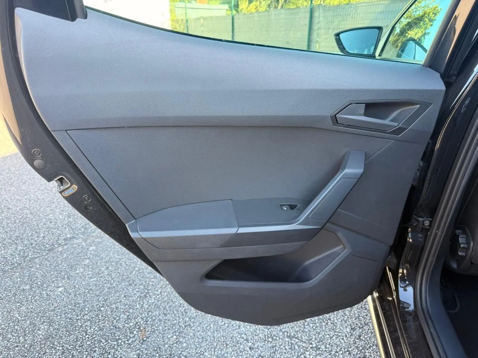 Vue intérieure de la porte arrière droite noire de la SEAT IBIZA 2025 avec poignée et commande de fenêtre intégrée.
