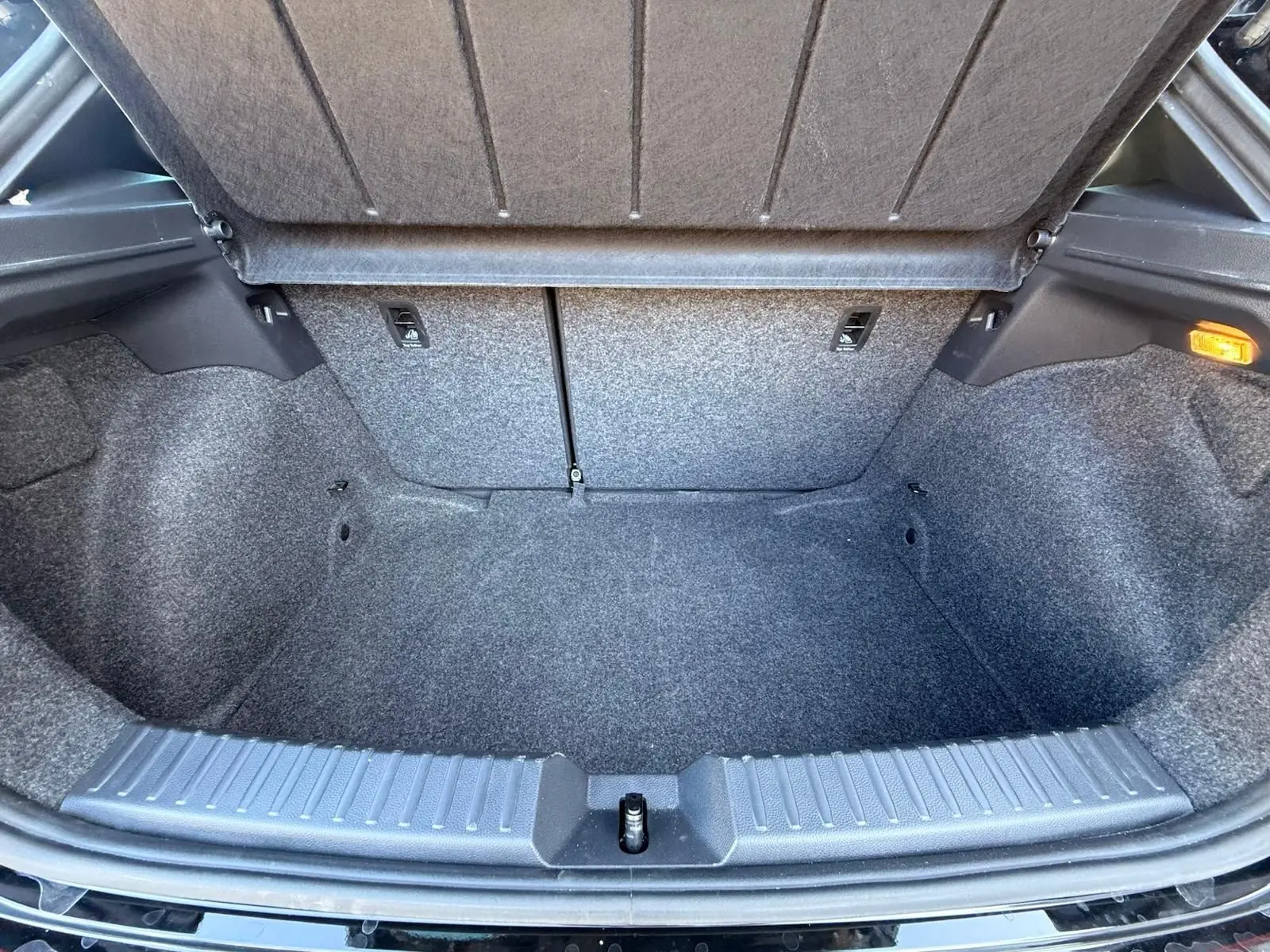 Coffre ouvert de la SEAT Ibiza 1.0 TSI 95 FR noir, vue intérieure montrant l'espace de rangement et la moquette grise.
