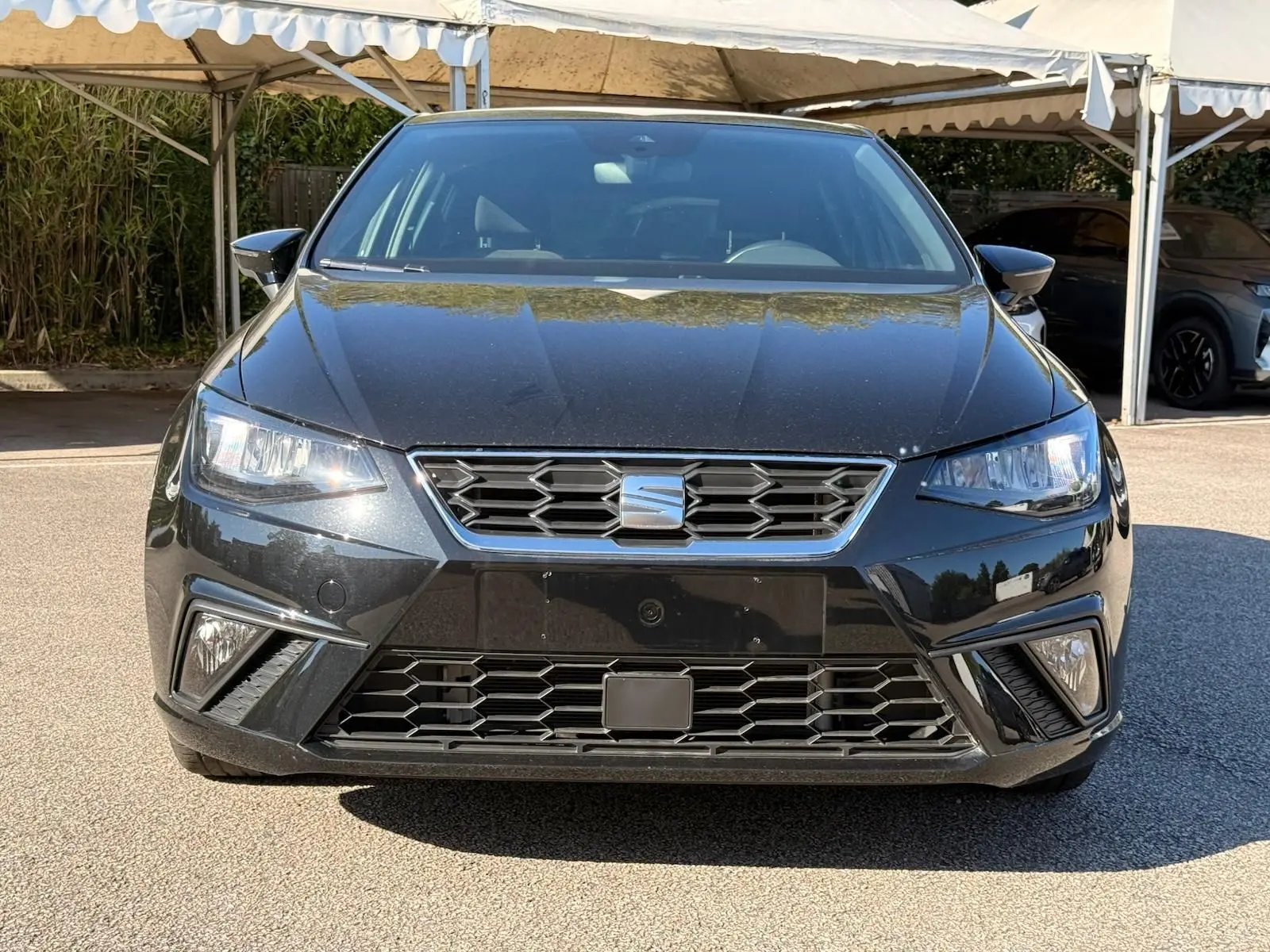 Vue avant d'une SEAT Ibiza 1.0 TSI 95 FR noire, avec calandre hexagonale et feux LED allumés.