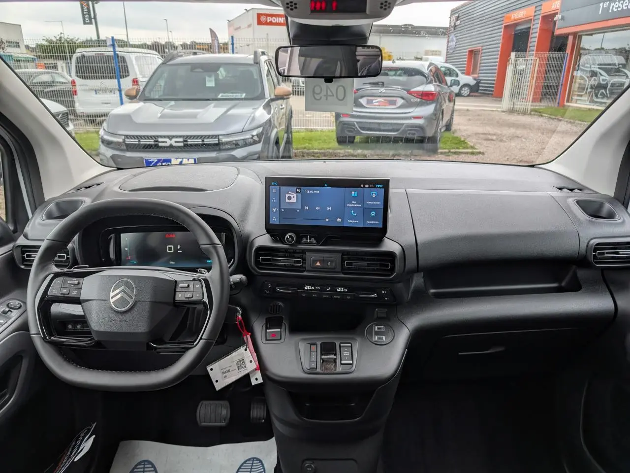Vue intérieure avant du tableau de bord du Citroën Berlingo blanc 2025 avec écran tactile et volant multifonctions cuir.