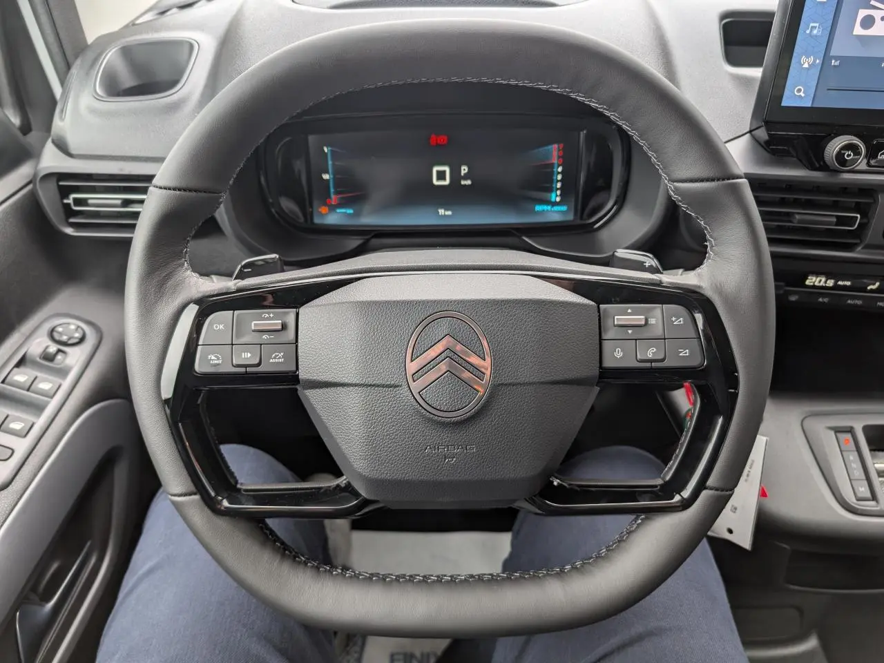 Vue intérieure centrée sur le volant cuir multifonctions noir du Citroën Berlingo 2025 avec tableau de bord numérique.