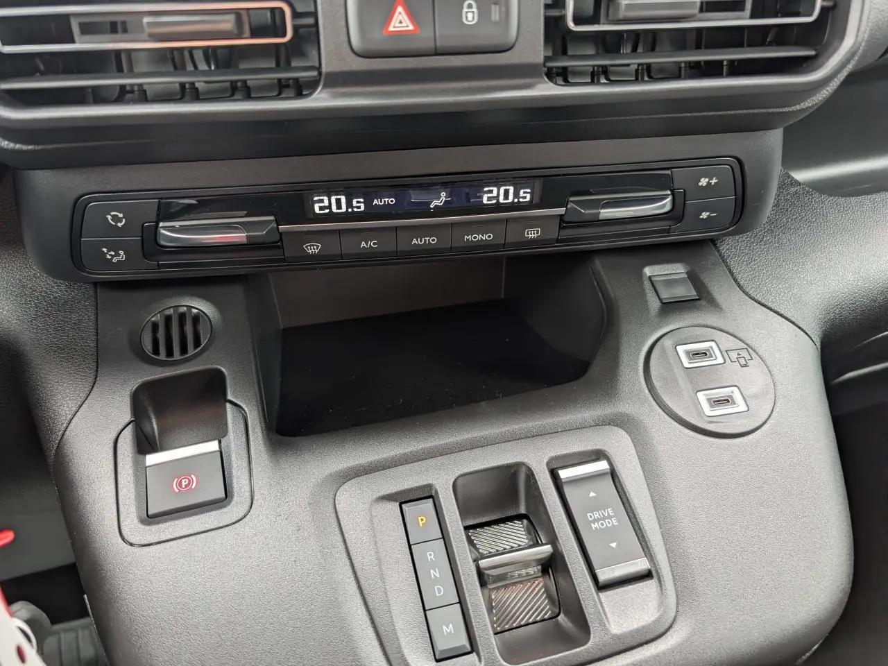 Vue rapprochée de la console centrale noire du Citroën Berlingo 2025 avec commandes climatisation et boîte auto.