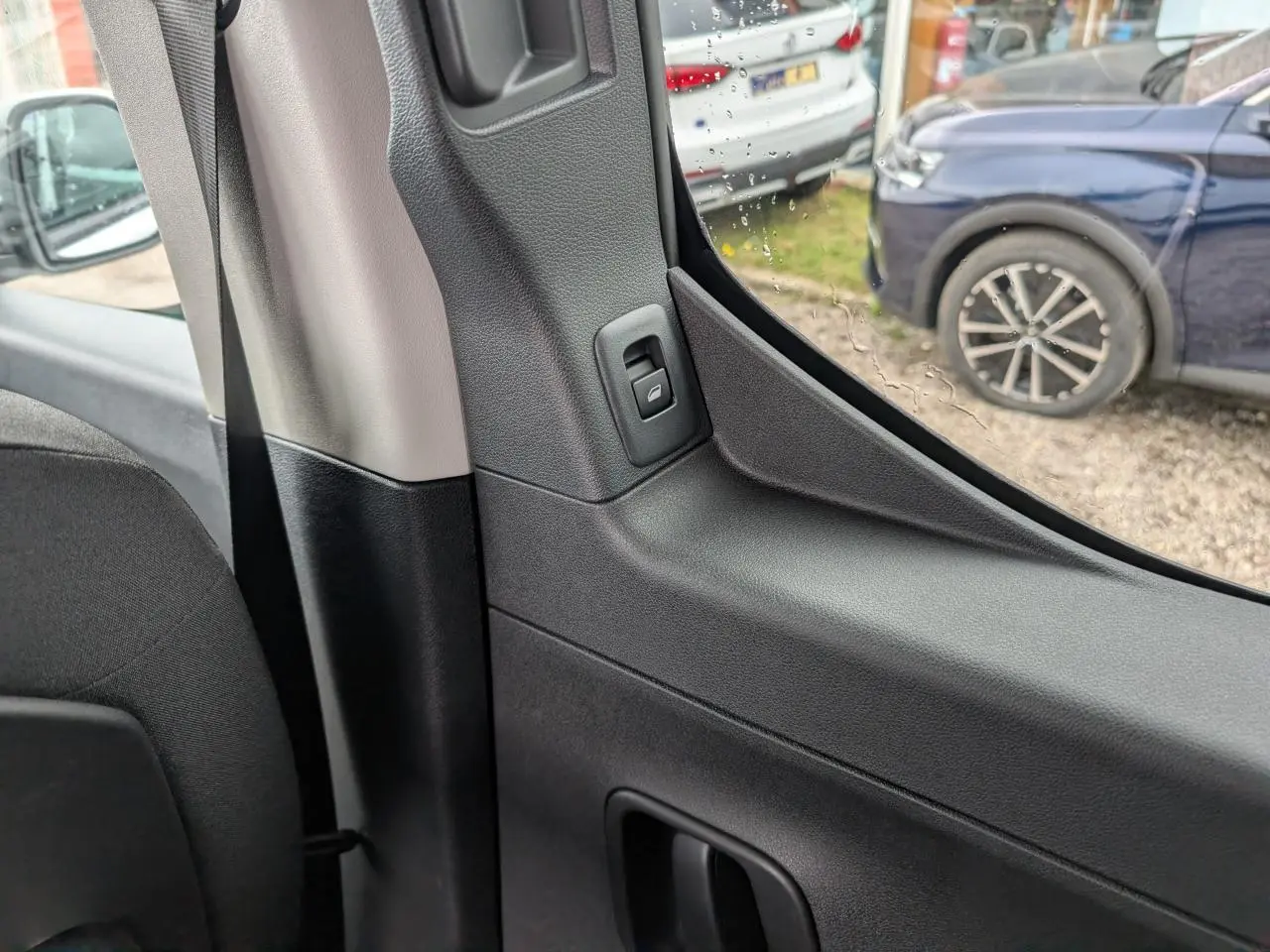 Détail intérieur côté gauche montrant la poignée et la commande de la porte coulissante du Citroën Berlingo blanc.