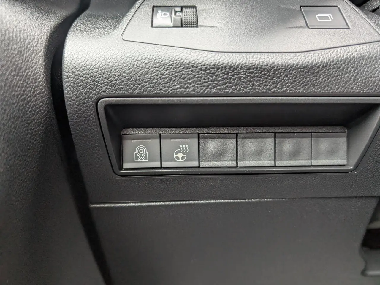 Gros plan sur les boutons de commande noirs du tableau de bord côté conducteur du Citroën Berlingo blanc 2025.