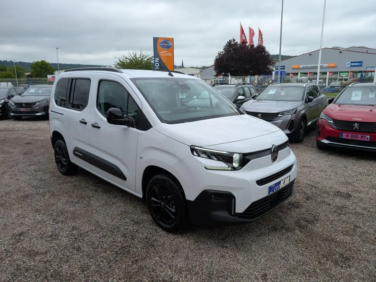 Vue 3/4 avant d'un Citroën Berlingo blanc Kaolin avec barres de toit noires et jantes alliage noires.