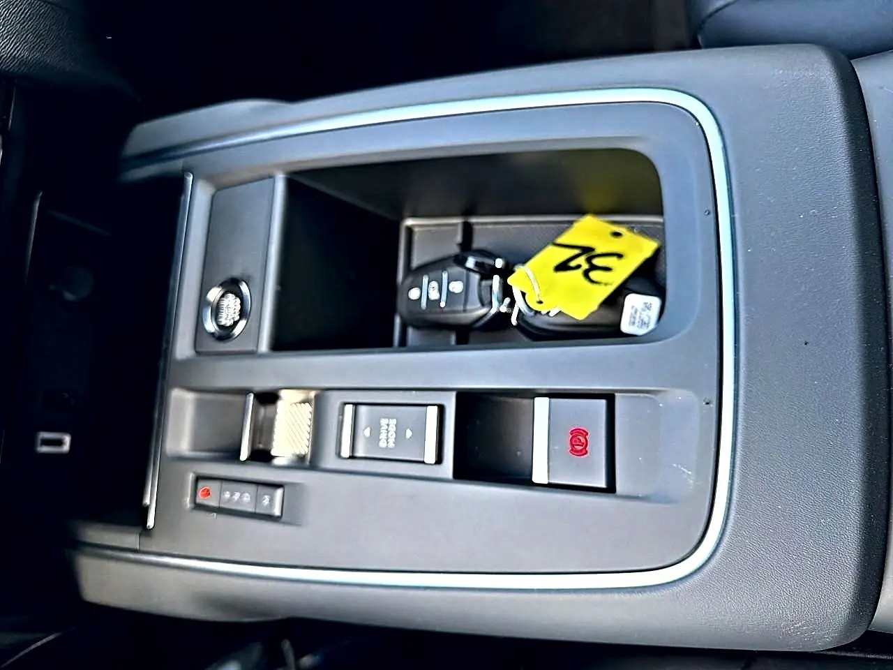 Vue rapprochée de la console centrale grise avec clé et bouton de frein à main électrique dans Citroën C5 Aircross blanc.