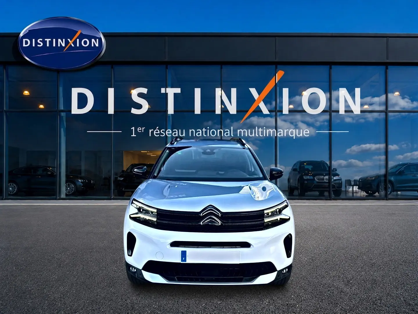 Citroën C5 Aircross blanc vue de face avec calandre noire et barres de toit devant showroom Distinxion.