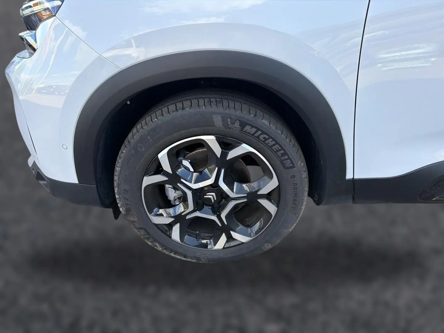Gros plan sur la roue avant droite du Citroën C5 Aircross blanc avec jante alliage noire et argentée.