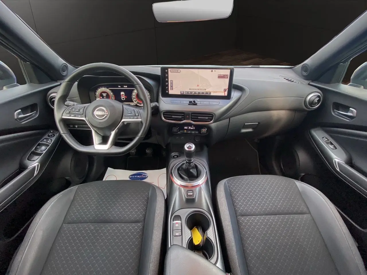 Intérieur noir du Nissan Juke 2025 vu de face, avec tableau de bord digital et écran tactile central.