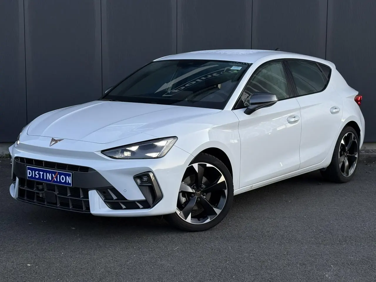 Vue 3/4 avant droite d'une CUPRA Leon blanche Neige avec jantes alliage noires et logo CUPRA sur calandre.