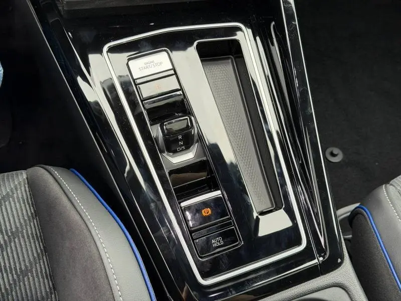 Gros plan sur la console centrale noire brillante de la Volkswagen Golf 2.0 TDI 150ch R-Line avec levier de vitesse automatique et bouton start/stop.