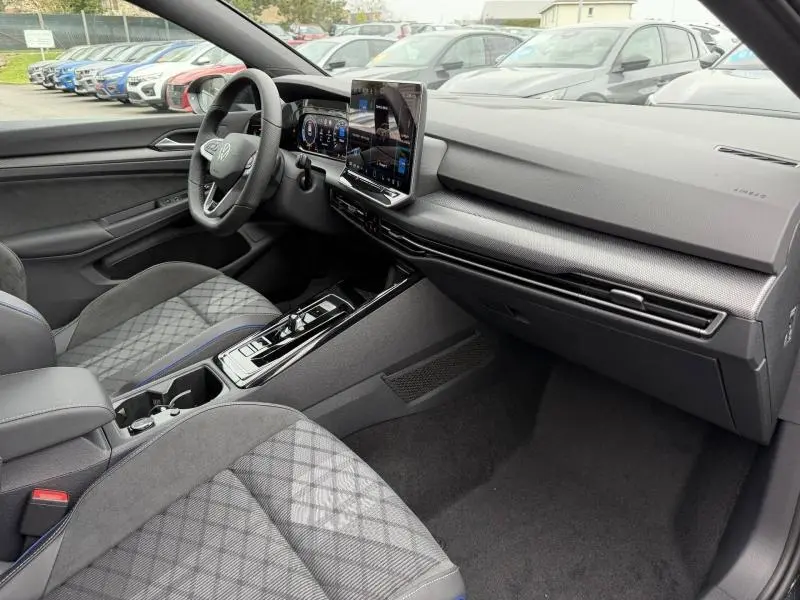 Vue intérieure côté conducteur de la Volkswagen Golf 2.0 TDI 150ch R-Line 2026 avec sièges tissu à motif et tableau de bord moderne.
