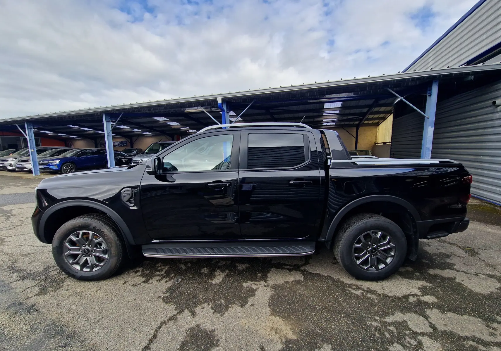 Vue de profil côté gauche du Ford Ranger Double Cabine noir 2023 avec marchepied et rideau de plateau coulissant.