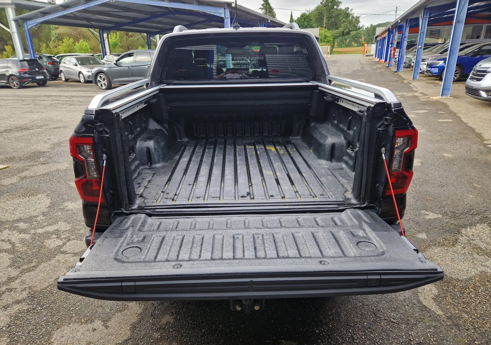 Vue arrière du Ford Ranger Double Cabine noir 2023 avec benne ouverte et rideau de plateau coulissant visible.