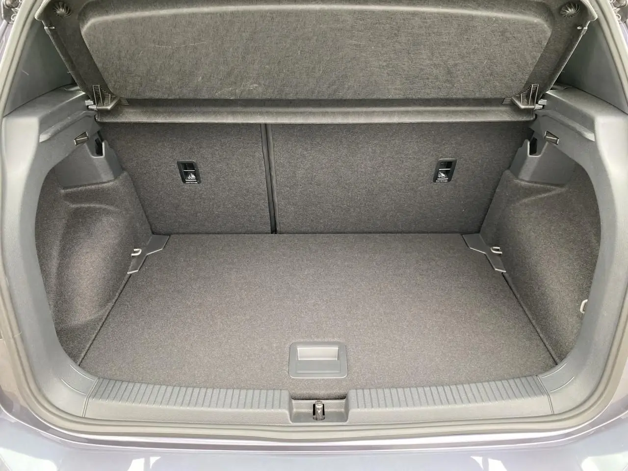 Coffre ouvert gris du Volkswagen T-Cross 2024, vue intérieure montrant l'espace de rangement et la moquette.