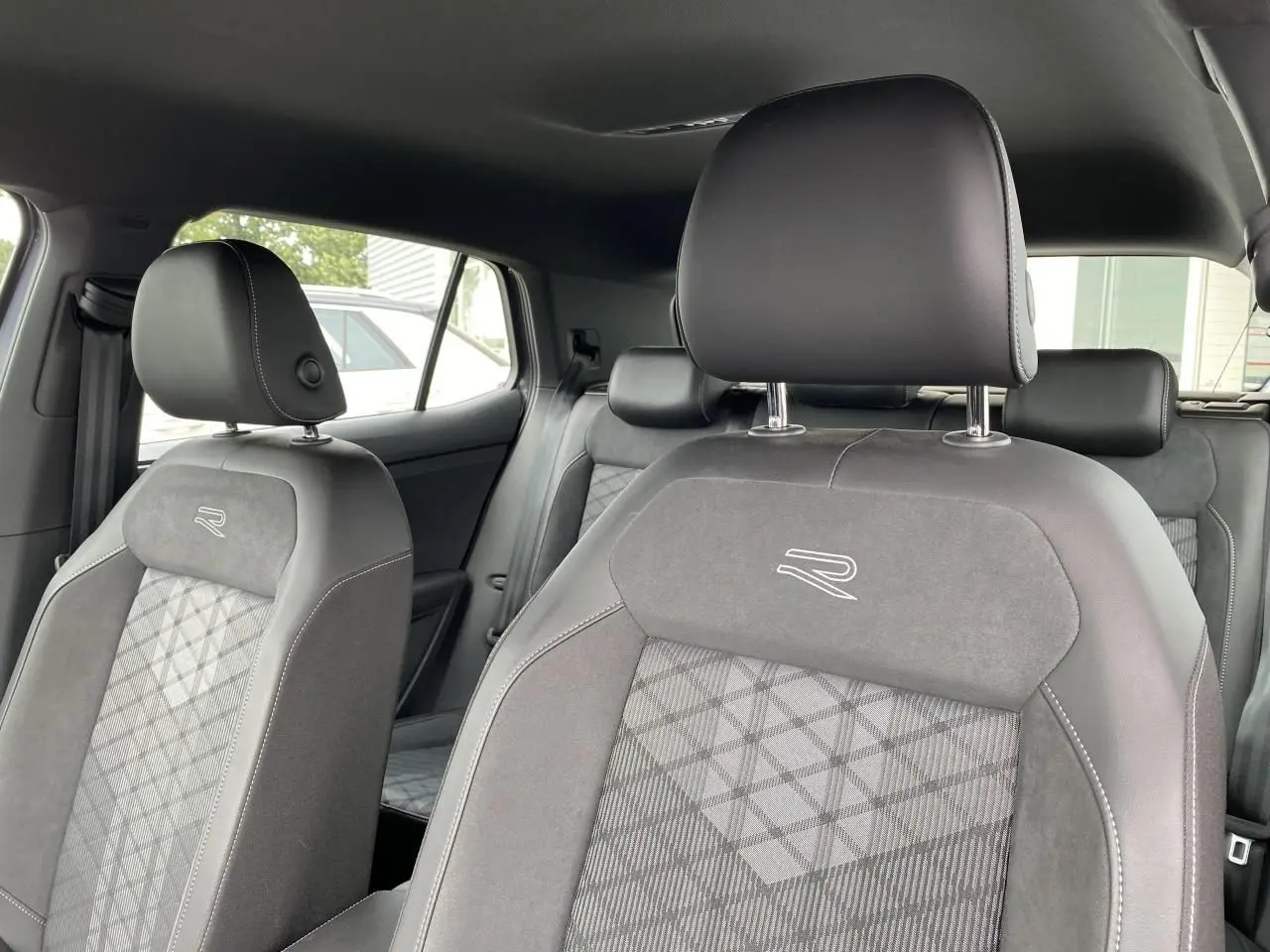Gros plan sur les sièges avant gris du Volkswagen T-Cross 2024 avec logo R brodé et finition mixte cuir/alcantara.