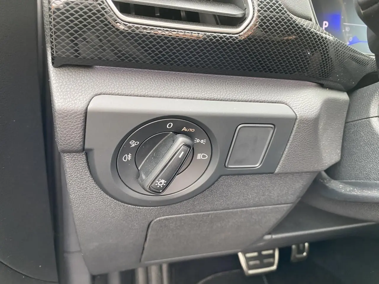 Gros plan sur le bouton de commande des phares dans l’habitacle gris du Volkswagen T-Cross 2024 côté gauche.
