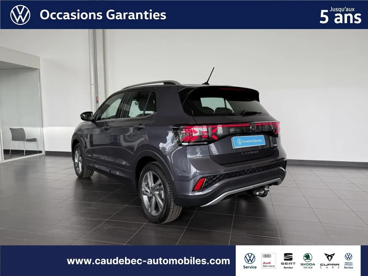 Volkswagen T-Cross gris vue 3/4 arrière droit en intérieur, avec attelage amovible et feux arrière LED.