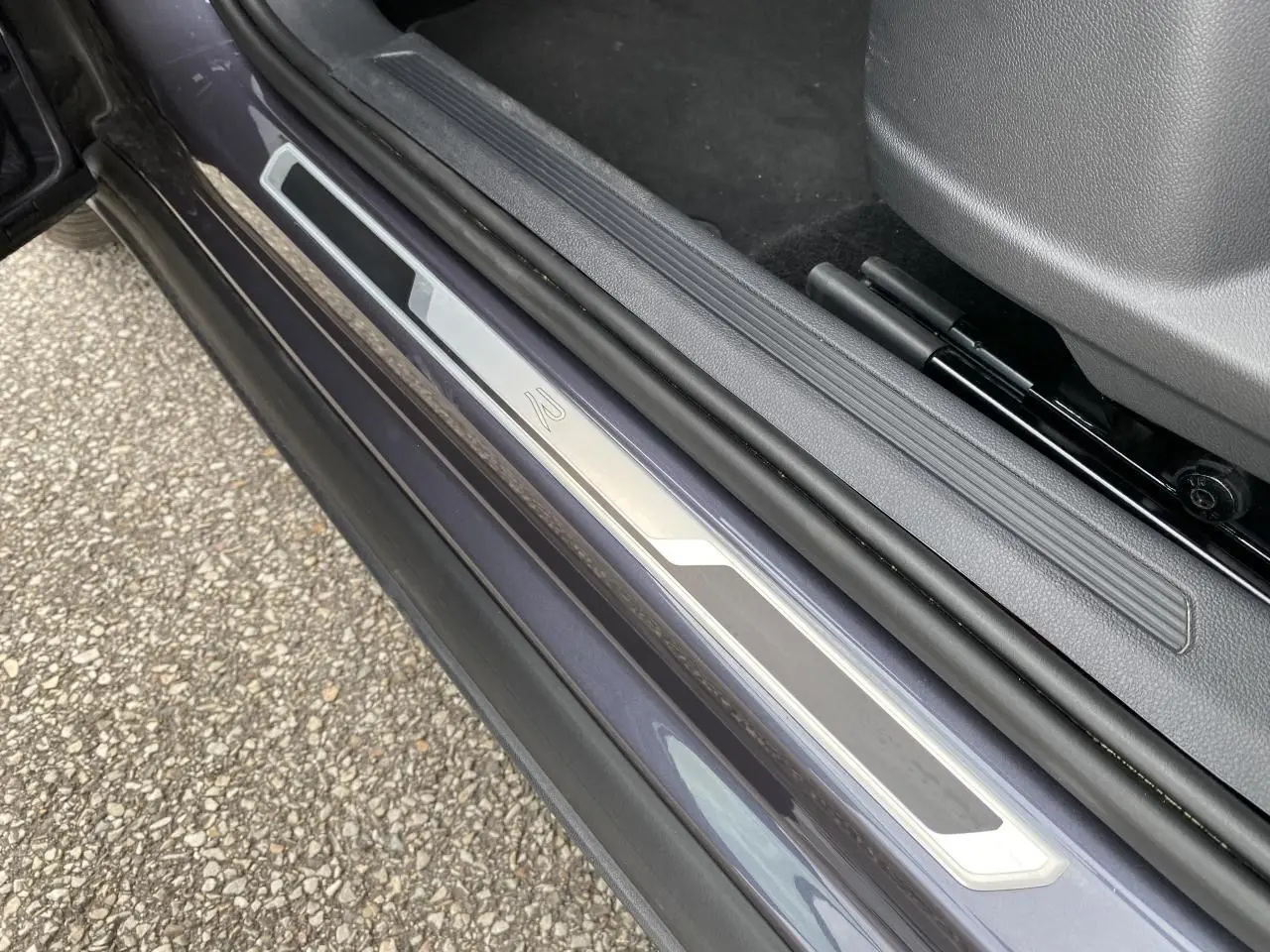 Gros plan sur le seuil de porte côté conducteur gris métallisé du Volkswagen T-Cross 2024 avec logo R-Line.