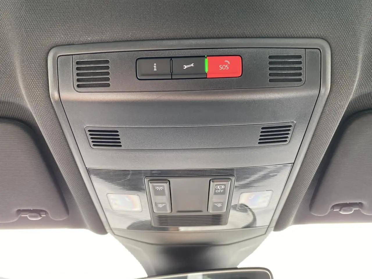 Vue intérieure du plafonnier gris foncé du Volkswagen T-Cross 2024 avec boutons SOS et éclairage intégré.