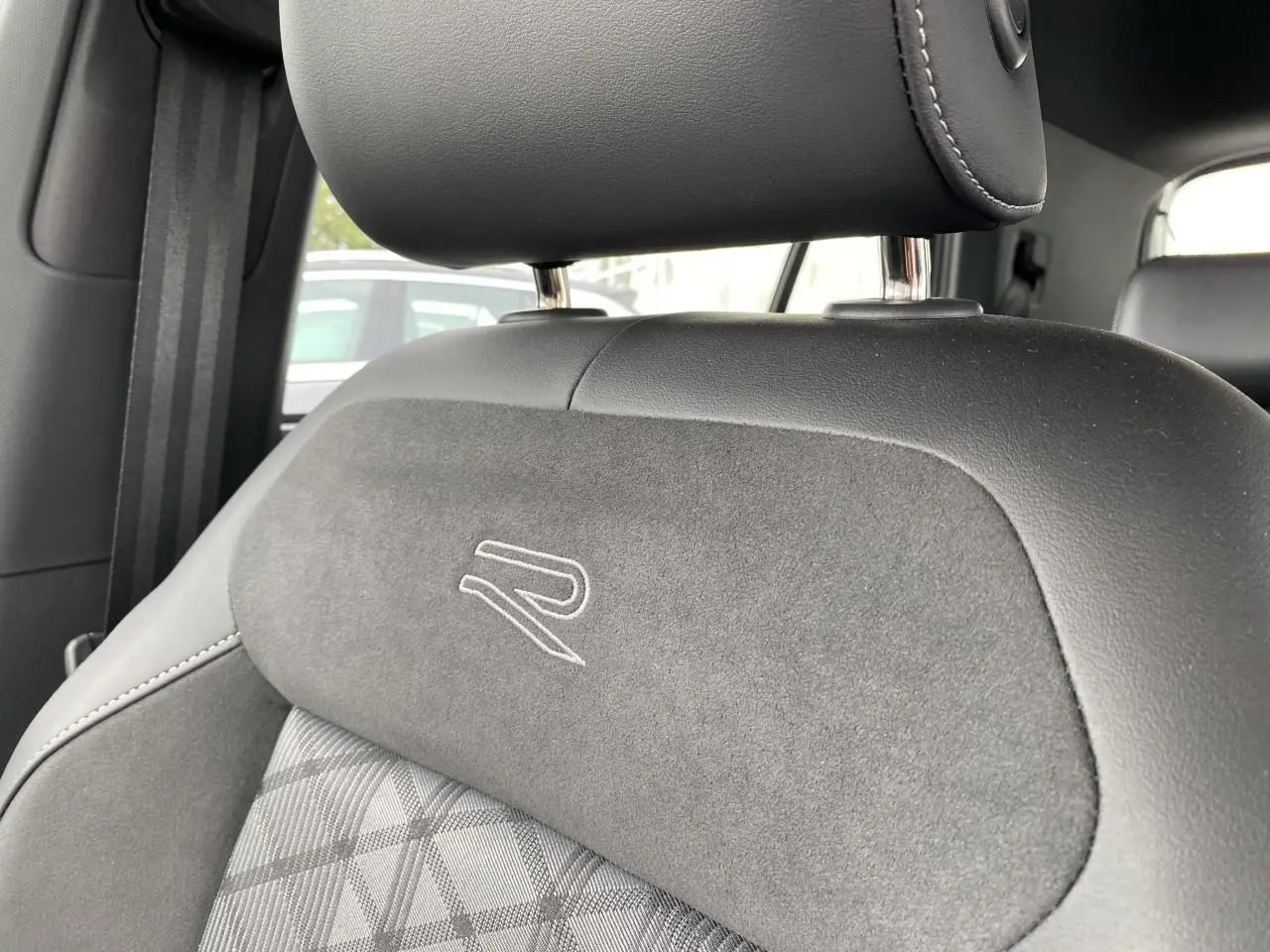 Gros plan sur l’appuie-tête et dossier de siège avant gris foncé avec logo R brodé, intérieur Volkswagen T-Cross.