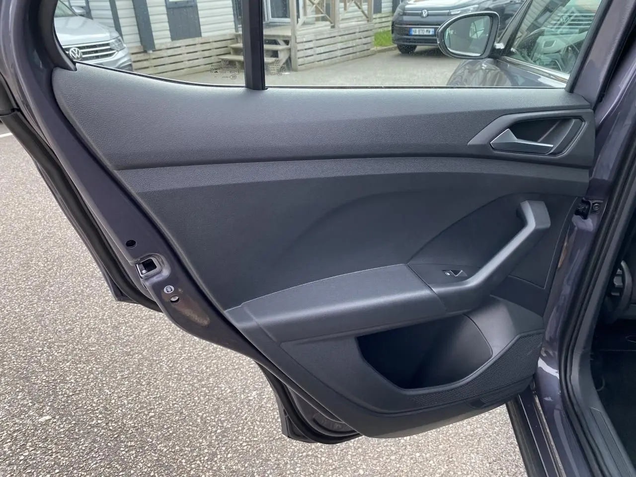 Vue intérieure de la porte arrière droite grise du Volkswagen T-Cross 2024 avec poignée et commande de vitre.
