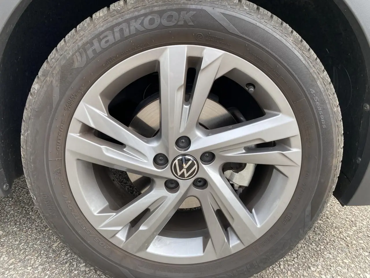 Gros plan sur la roue avant droite avec jante alliage grise et logo Volkswagen au centre.