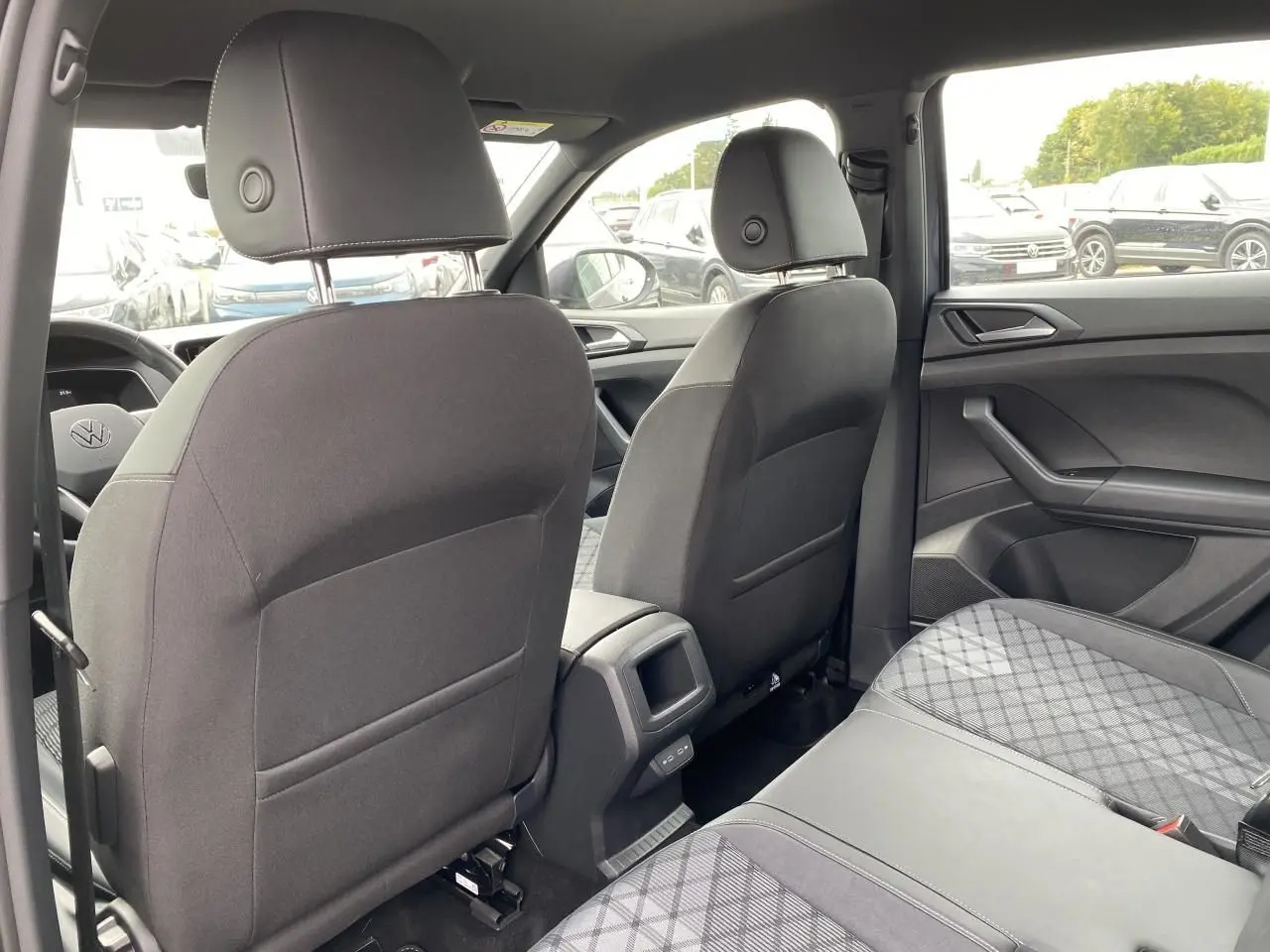 Vue intérieure arrière du Volkswagen T-Cross gris, montrant les sièges avant et la banquette arrière en tissu.
