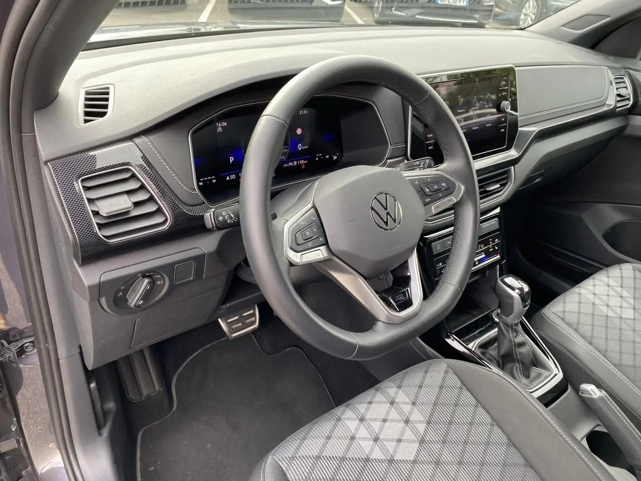 Vue intérieure côté conducteur du Volkswagen T-Cross gris 2024, volant cuir multifonction et tableau de bord digital.